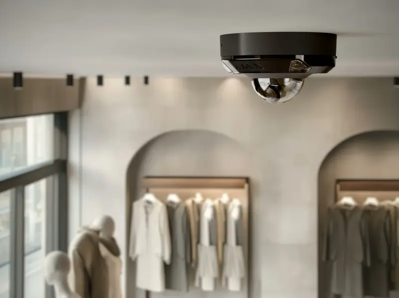 Caméra dôme Ajax DomeCam Mini noire au plafond d'un magasin de vêtements, vue rapprochée