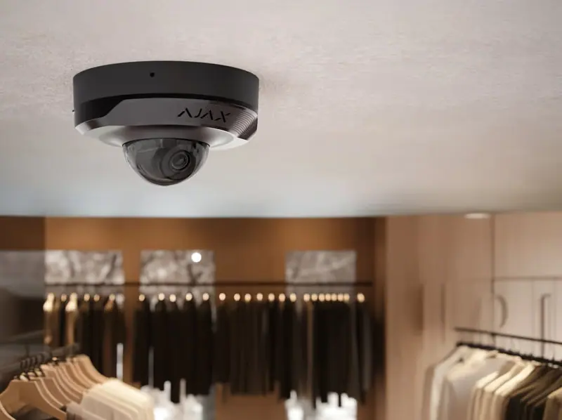 Caméra dôme Ajax DomeCam Mini noire installée au plafond d'une boutique de prêt-à-porter