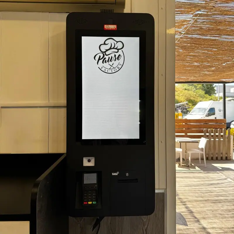 Borne de commande tactile avec terminal de paiement installée à l'entrée d'un snack