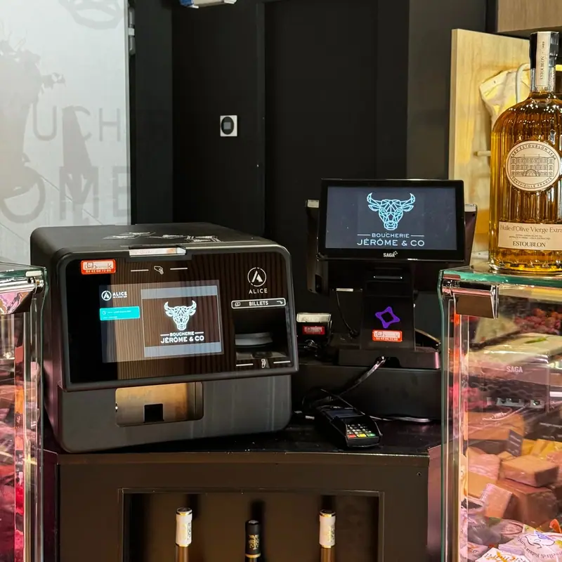 Monnayeur automatique et caisse tactile installés derrière la vitrine réfrigérée d'une boucherie