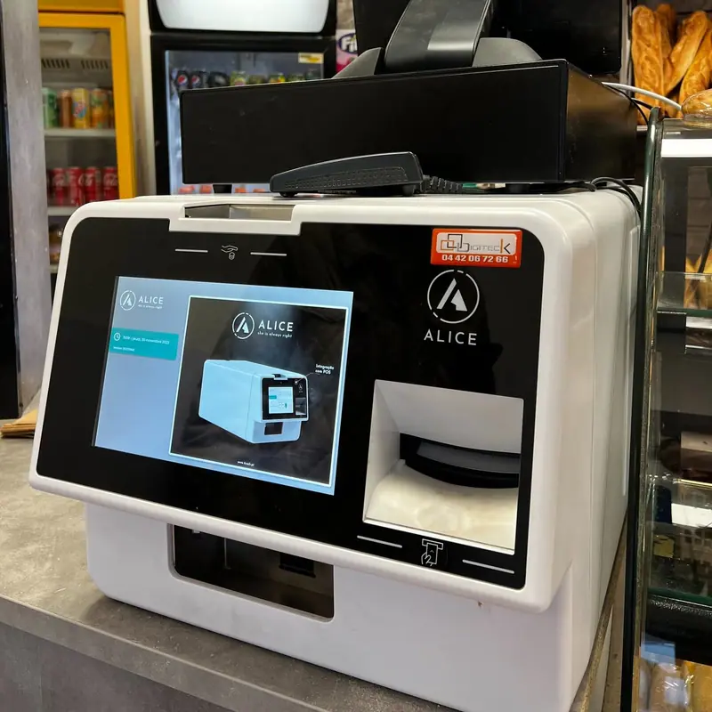 Monnayeur automatique blanc posé sur le comptoir d'une boulangerie, rendu de monnaie automatique
